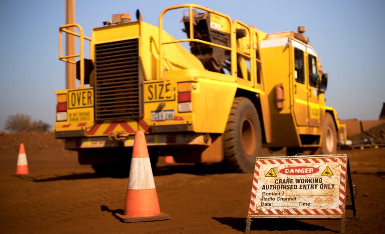 Danger crane lifting working operation sign authorised entry person only with defocused track crane at the background construction mine site, Sydney, Australia