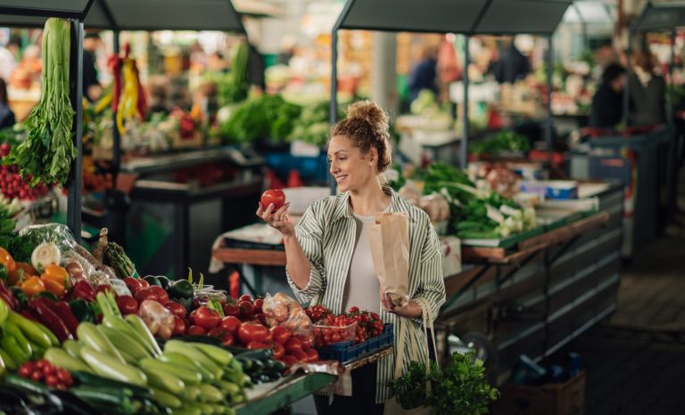 Portrait,Of,Female,Customer,Standing,Near,Market,Stall,With,Paper