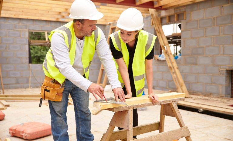 Carpenter with female apprentice working on building site