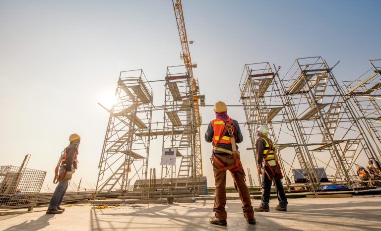 Construction engineers supervising progress of construction project stand on new